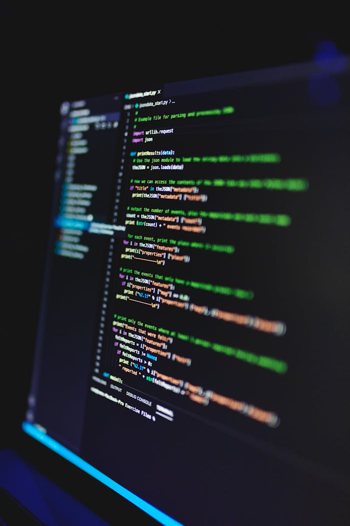 Vertical shot of colorful programming code on a screen in a dark room, highlighting technology work.